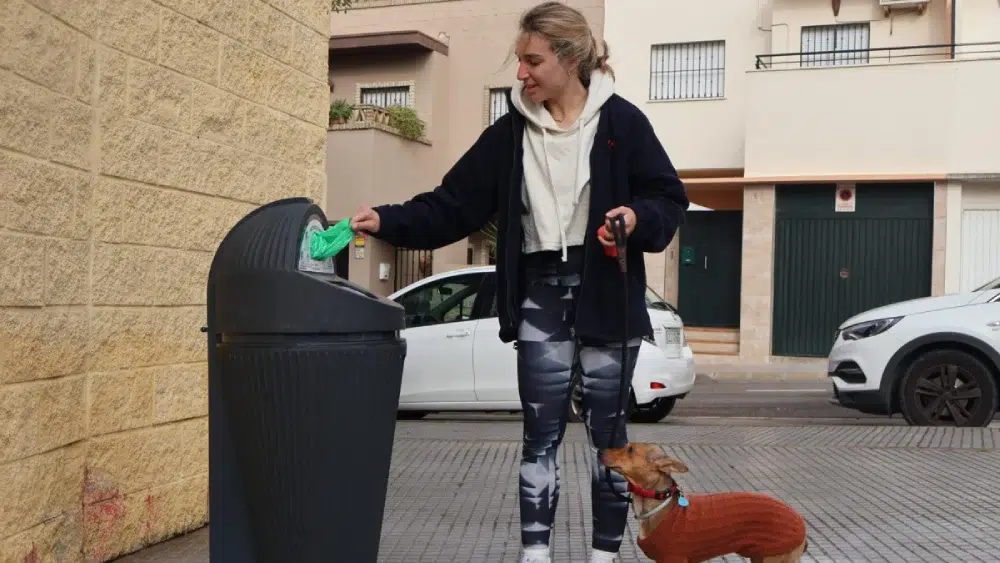 Joven tirando una bolsa con excrementos de su mascota a la papelera / Ayuntamiento de Alcalá