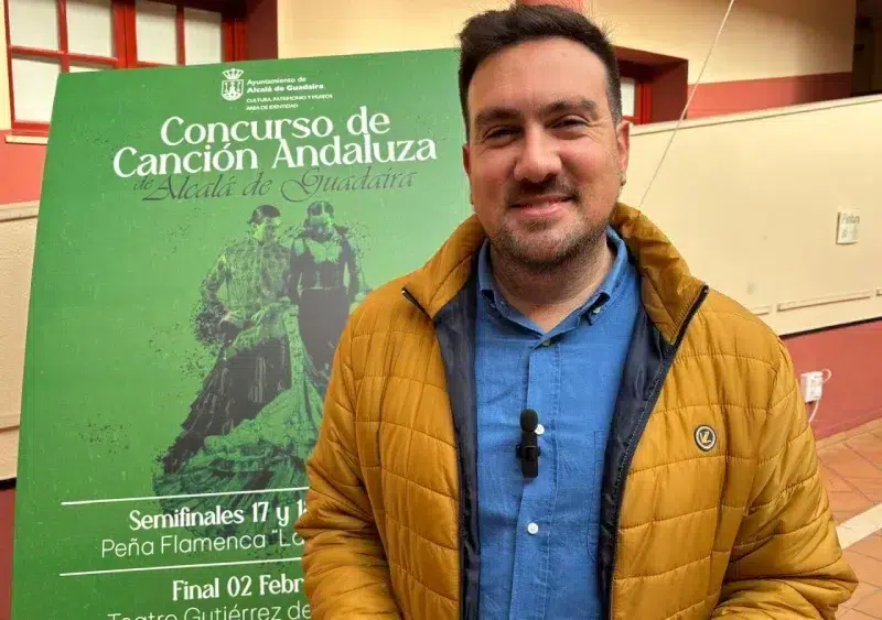 Christopher Rivas frente al cartel de presentación del concurso / Ayuntamiento de Alcalá de Guadaíra