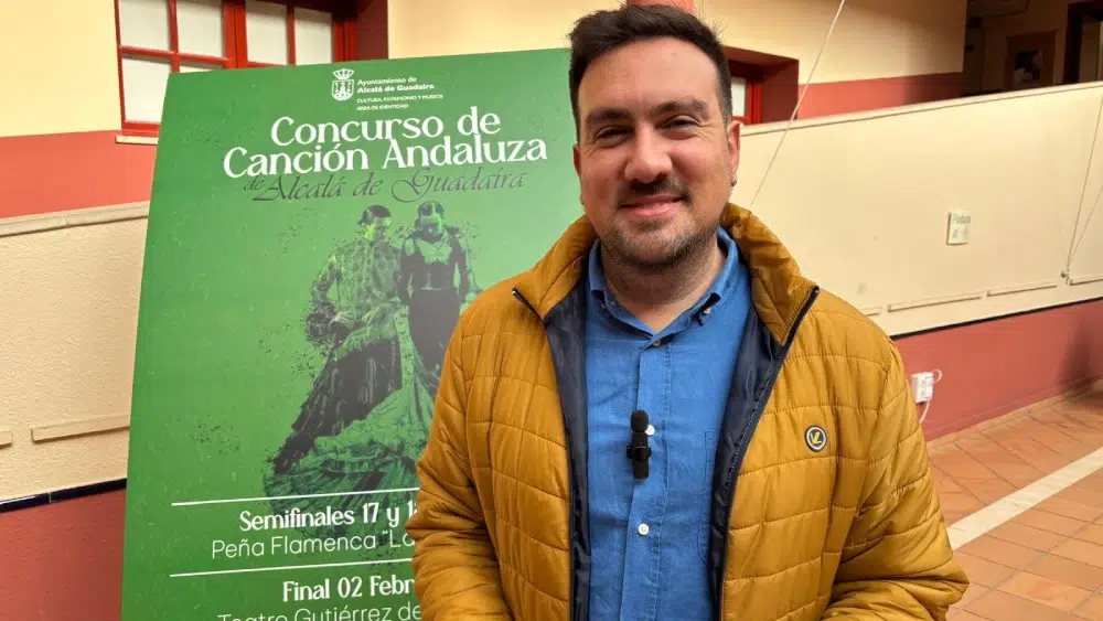 Christopher Rivas frente al cartel de presentación del concurso / Ayuntamiento de Alcalá de Guadaíra